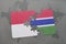 puzzle with the national flag of indonesia and gambia on a world map background.