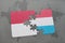 puzzle with the national flag of indonesia and luxembourg on a world map background.