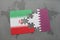 puzzle with the national flag of iran and qatar on a world map background.