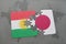 puzzle with the national flag of kurdistan and japan on a world map background.