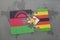 puzzle with the national flag of malawi and zimbabwe on a world map