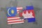 puzzle with the national flag of malaysia and cambodia on a world map background.
