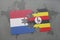 puzzle with the national flag of netherlands and uganda on a world map background.