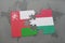 puzzle with the national flag of oman and hungary on a world map background.