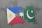 puzzle with the national flag of philippines and pakistan on a world map background.