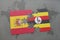 puzzle with the national flag of spain and uganda on a world map background.