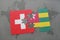 puzzle with the national flag of switzerland and togo on a world map background.