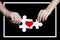 Puzzle with a red heart in the hands of a loving couple in a white frame. Valentine`s day concept.On a black background