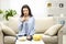 Puzzled brunette woman is thinking which snack to choose, isolated, sitting on the couch at home.