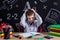 Puzzled excellent schoolboy sitting on the desk with books, school supplies, with both arms on the head