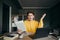 Puzzled guy sitting at home at table on the background of the bedroom with a book in hand, emotionally looking at the camera with