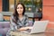 Puzzled tired female freelancer makes online research of information, wrapped in warm coverlet, poses against cafe interior. Attra