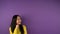 Puzzled young asian woman in bright yellow sweater looks right. Free space for text and speech bubble. isolated purple