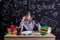 Puzzled youngster sitting at the desk with a head leaned on the hand with pointing finger under the head, with a pen in