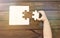 Puzzles. puzzle piece in hand on a wooden background