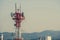 Pylon of Telecommunications with antennas for radio, television and telephone signal broadcasting in a cloudy blue sky.