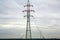 Pylons and power lines with vibrant sky, clouds and sun.