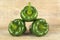 Pyramid made of three green bell peppers on wooden plank