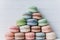 Pyramid of multicolored macarons or macaroons on a white wooden background, almond pastel tones