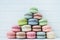 Pyramid of multicolored macaroons on a white wooden background