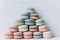 Pyramid of multicolored macaroons on a white wooden background, almond cookies in pastel tones