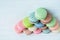 Pyramid of multicolored macaroons on a white wooden background, almond cookies in pastel tones. Top view, copy space