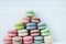 Pyramid of multicolored macaroons on a white wooden background, copy space