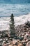 Pyramid of pebbles on the beach on a background of the sea wave. Stability, balance and harmony, vacation at sea