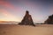 Pyramid sea stack on beach with beautiful sunrise sky with red clouds