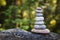 Pyramid stones balance on a tree trunk in the forest. Pyramid in focus, forest background is blurred