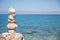 Pyramid of stones at the ocean. Blue water background.