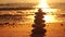 Pyramid stones on the seashore with warm sunset on the sea ocean background. Happy holidays. Sandy beach, calm sea