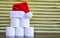 A pyramid of toilet paper  with a Santa Claus hat against a gold background