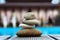Pyramid of various sea pebbles on the edge of the pool and against the background of gazebos for relaxation. The concept of life