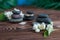 Pyramids of gray zen stones with flowers, green leaves on wooden background. Concept of harmony, balance and meditation,