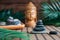 Pyramids of gray zen stones with green leaves and Buddha statue. Concept of harmony, balance and meditation, spa, massage, relax