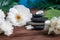 Pyramids of gray zen stones with white flowers, green leaves on wooden background. Concept of harmony, balance and meditation,