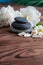 Pyramids of gray zen stones with White flowers, green leaves on wooden background. Concept of harmony, balance and meditation,