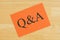 Q&A on a orange card with a pen on textured wood background
