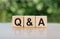 Q&A - question and answer, word written on wooden blocks. The text is written in black letters and is reflected in the mirror