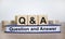 Q and A, questions and answers symbol. Concept words `Q and A questions and answers` on wooden cubes on book on a beautiful whit