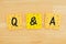 Q&A on three sticky notes on textured desk wood