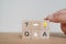 Q and A word on wood cube blocks with senior`s hand holding lightbulb icon on table with grey background