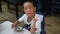 Qingyuan, China - June 23, 2016: A little curious Chinese boyis eating his meal and talking with his classmates