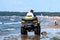 Quad bike on the beach on a dusty yellow background. Landscape blue background. Seascape. Summer landscape in the background.