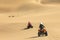 Quad driving people - two happy bikers in sand desert.