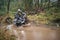 Quad rider jumping on a muddy forest trail