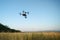 Quadcopter with camera flying over field. Photography quadcopter drone hovering over young green sprouts of wheat plants