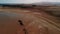 Quadcopter flight over the Red Sea. Low tide. Sand. Desert. Hotel and mountains in the distance. People walk along the shore.