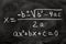 Quadratic equations handwritten on a blackboard with chalk